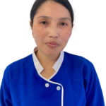 Portrait of a woman in a blue medical uniform, facing the camera against a white background, suggesting a healthcare professional