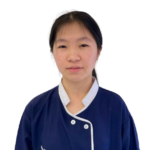 Portrait of a woman in a dark blue, white-trimmed uniform, facing camera with a neutral expression, likely staff member at a center (text on uniform reads 'Valence Center').