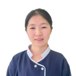 Front-facing portrait of a young woman in navy medical scrubs with white trim, looking at the camera.