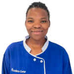 Portrait of a smiling person wearing a blue uniform with white trim; Excellence Center logo on the chest visible.