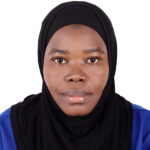 Portrait of a Black woman wearing a black hijab and blue top, facing the camera with a neutral expression against a white background.