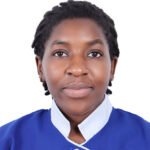 Close-up portrait of a young Black woman with short twists, wearing a blue uniform with a white collar against a white background, looking at the camera with a neutral expression.