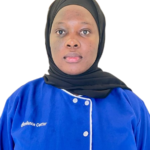 Portrait of a woman wearing a black hijab and a blue uniform facing the camera, with 'Excellence Center' embroidered on the chest.