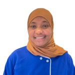 Portrait of a smiling woman wearing a brown hijab and a blue uniform with an 'Excellence Center' logo on the chest.