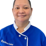 Portrait of a smiling woman in a blue chef-style uniform with white trim, featuring 'Excellence Center' text on the chest.