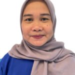 Portrait of a smiling woman wearing a light gray hijab and a blue shirt against a white background, facing the camera.