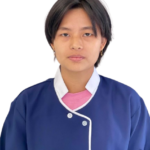 Portrait of a person with short black hair wearing a blue uniform with white trim and a pink shirt, facing the camera.