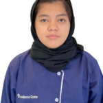 Portrait of a woman wearing a black hijab and a blue uniform with the Excellence Center logo, facing the camera.