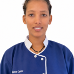 Portrait of a young woman in a blue chef jacket with white trim, looking at the camera.