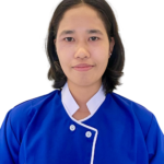 Person wearing a blue medical uniform with white trim, facing the camera with a neutral expression.