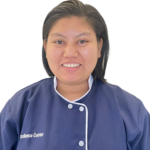 Smiling woman in a navy uniform with white piping, left chest reads 'Excellence Center', against a white background.