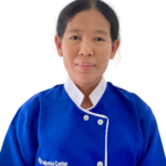 Portrait of a woman wearing a blue uniform with a white collar, facing the camera.