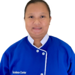 Portrait of a woman smiling in a blue uniform with white trim, against a white background; uniform reads 'Excellence Center' on the left.
